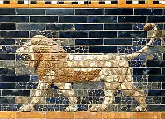 Reliéf lva vytvořený z glazovaných cihel, jde o samce, který kráčí směrem doleva