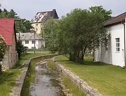 Sázek protékající Skalnou. V pozadí hrad Vildštejn