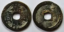 Fotografie dvou mincí, jedna z lícové, druhá rubové strany, mince jsou kulaté, zašlé, s čtvercovým otvorem uprostřed, na líci po stranách otvoru nápis tvořený čtyřmi znaky čínského písma