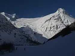 Fotografie zachycuje kontrast mezi sluncem osvícenými a zastíněnými zasněženými svahy hor