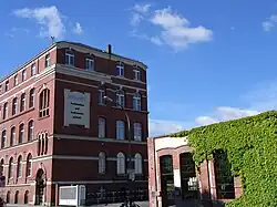 Barevná fotografie s budovou z červených cihel a popínavého břečťanu