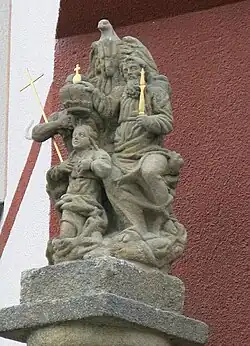 Sousoší s postavami klečící Panny Marie, Boha Otce a Ježíše Krista na vrcholu barokního sloupu