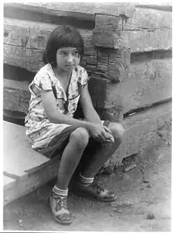 Holčička sedící u srubu