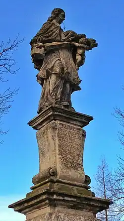 Vrcholová část sochy světce, modrá obloha