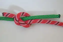 Krok 1: První uzel (červené lanko) vedený „shora“ přes vodorovný (zelené lanko)