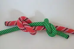 Krok 2: Druhý uzel (zelené lanko) vedený opět shodně „shora“ přes vodorovný (červené lanko)