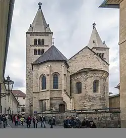 Na fotografii se tyčí románská část trojlodní baziliky svatého Jiří s apsidou nacházející se na Pražském hradě. Vyfocena je z Jiřské ulice směrem z východu.
