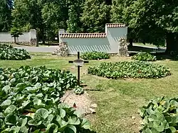 Pohled na hřbitov se zbytkem původní ohradní zdi, za silnicí viditelná brána nového lidického hřbitova