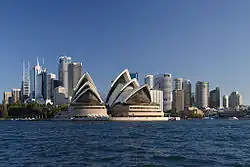 Opera v Sydney s mrakodrapy centrální obchodní oblasti ze zálivu Port Jackson