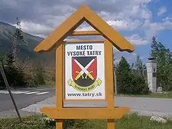 Znak Tatranských Zrubů, v pozadí pomník padlých letců