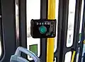 Tlačítko pro poptávkové otevírání dveří, umístěné na přidržovací tyči uvnitř vozidla; tramvaj T3, Praha, po roce 2000