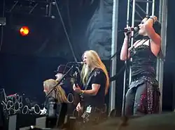 Zleva hraje Holopainen na klávesy, Vuorinen na kytaru, Hietala na baskytaru a zároveň zpívá a úplně napravo je zpěvačka Jansen s mikrofonem u úst. Foceno během koncertu v roce 2013.