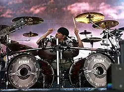 Jukka Nevalainen sedící za bicí soupravou a hrající na ni během vystoupení na festivalu Tuska Open Air 2013.