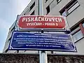 Tabule s názvem ulice Piskáčkových ve Vysočanech s modrou dodatkovou tabulí