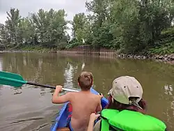 Vodáci projíždějící kolem zpevněného břehu bývalého přístavu
