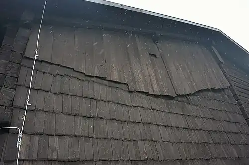 Ochrana stěn na návětrné straně vrstvou šindelů (dům čp. 71). Na snímku je také patrné utěsnění mezery mezi štítovou zdí a střechou přiraženou krokví.