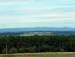 Pohled na vrch Hradiště (uprostřed) z východu ze svahu vrchu Louštín; vpravo kuželovitý vrch Pustý zámek