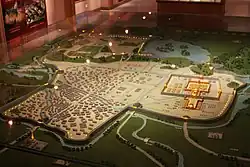 Plastický model města s domy, vodními toky, cestami, hradbami a zelenými plochami.