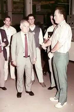 Šamir v obleku mezi skupinou mužů