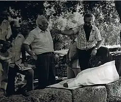 Kacir stojí mezi skupinou mužů a poslouchá