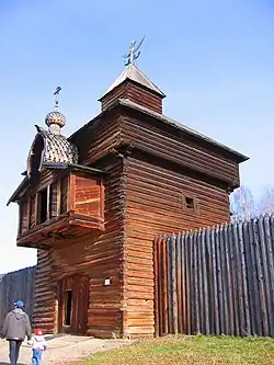 Barevná současná fotografie; vlevo a vpravo palisáda dvojnásobné výše člověka uprostřed s dřevěnou patrovou věží s věžičkou, věž zabírá většinu plochy snímku.