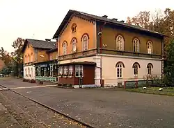 Dvoupodlažní budova se dvěma rizality po krajích. Spodní patro objektu je zděné, horní dřevěné. Před budovou se nachází nástupiště a kolejiště, za ní listnatý les.