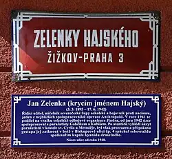 Tabule s názvem ulice Zelenky Hajského na Žižkově s modrou dodatkovou tabulí