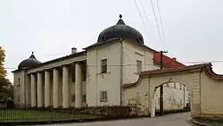 Čelní pohled na patrový kaštel. Po obou krajních stranách objektu jsou veže zakončené cibulovitou střechou. Mezi nimi stojí v čele přední strany objektu šest sloupů. Zcela vpravo je zděná brána jako vstup do areálu kaštelu.