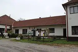 přízemní světle omítnutá budova s tmavě červenou střechou. U vchodu do objektu vlají dva prapory, jedním je slovenská vlajka, druhým vlajka Zemianského Podhradí. Před objektem se nachází oplocená zatravněná plocha se dvěma nástěnkami a informační tabulí.