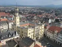 Barevná fotografie s pohledem na žitavské náměstí, uprostřed je radniční budova na čtvercovém půdoryse s věží