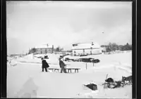 Im Vordergrund die Kamerabox sowie der Hund mit dem Schlitten. Der Hof der Familie Jobin im Hintergrund rechts ist erhalten geblieben